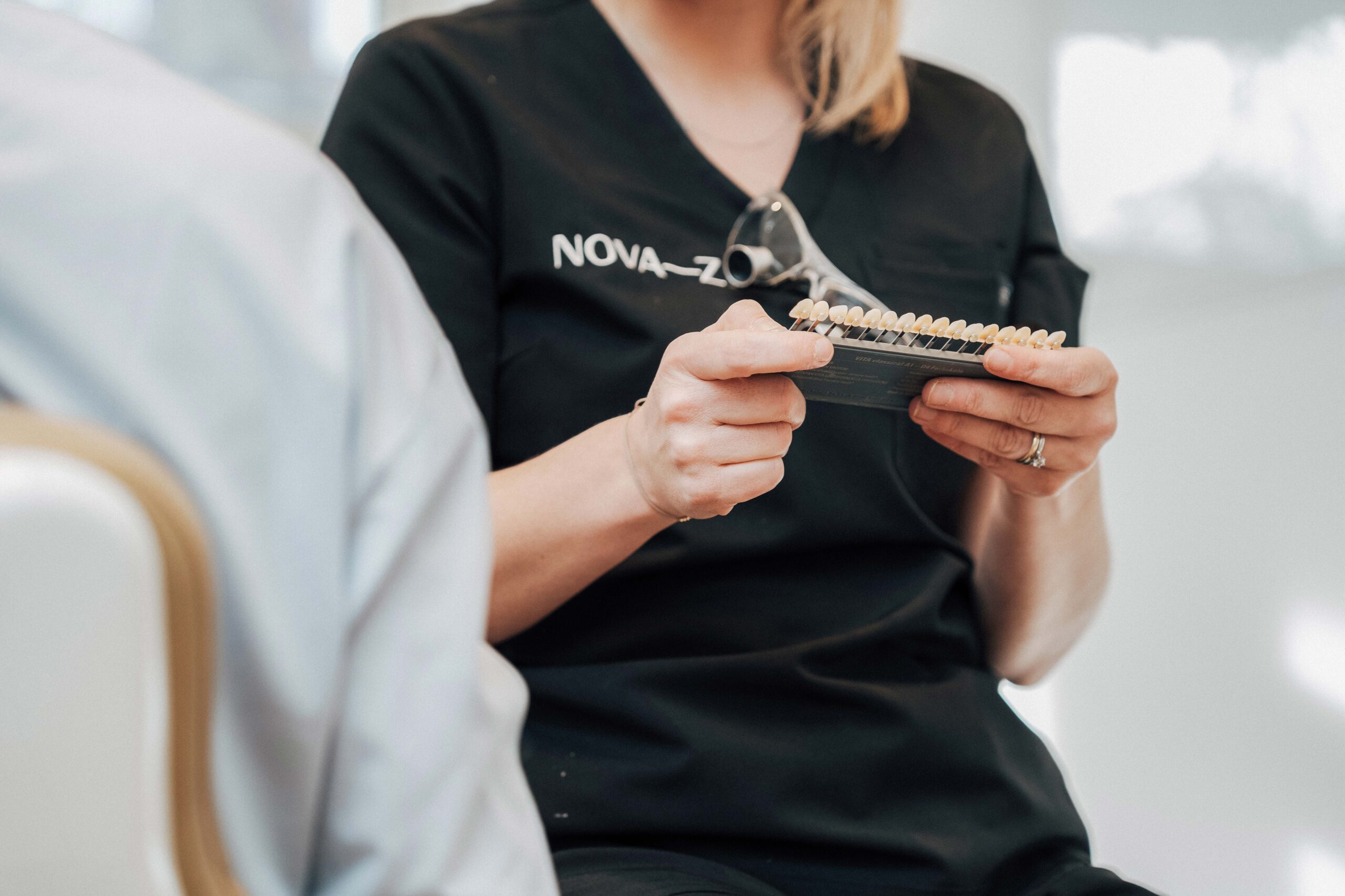 Eine Dentalhygienikerin von NOVA–Z hält eine Zahnfarbpalette zur Auswahl der Zahnfarbe beim Bleaching in den Händen