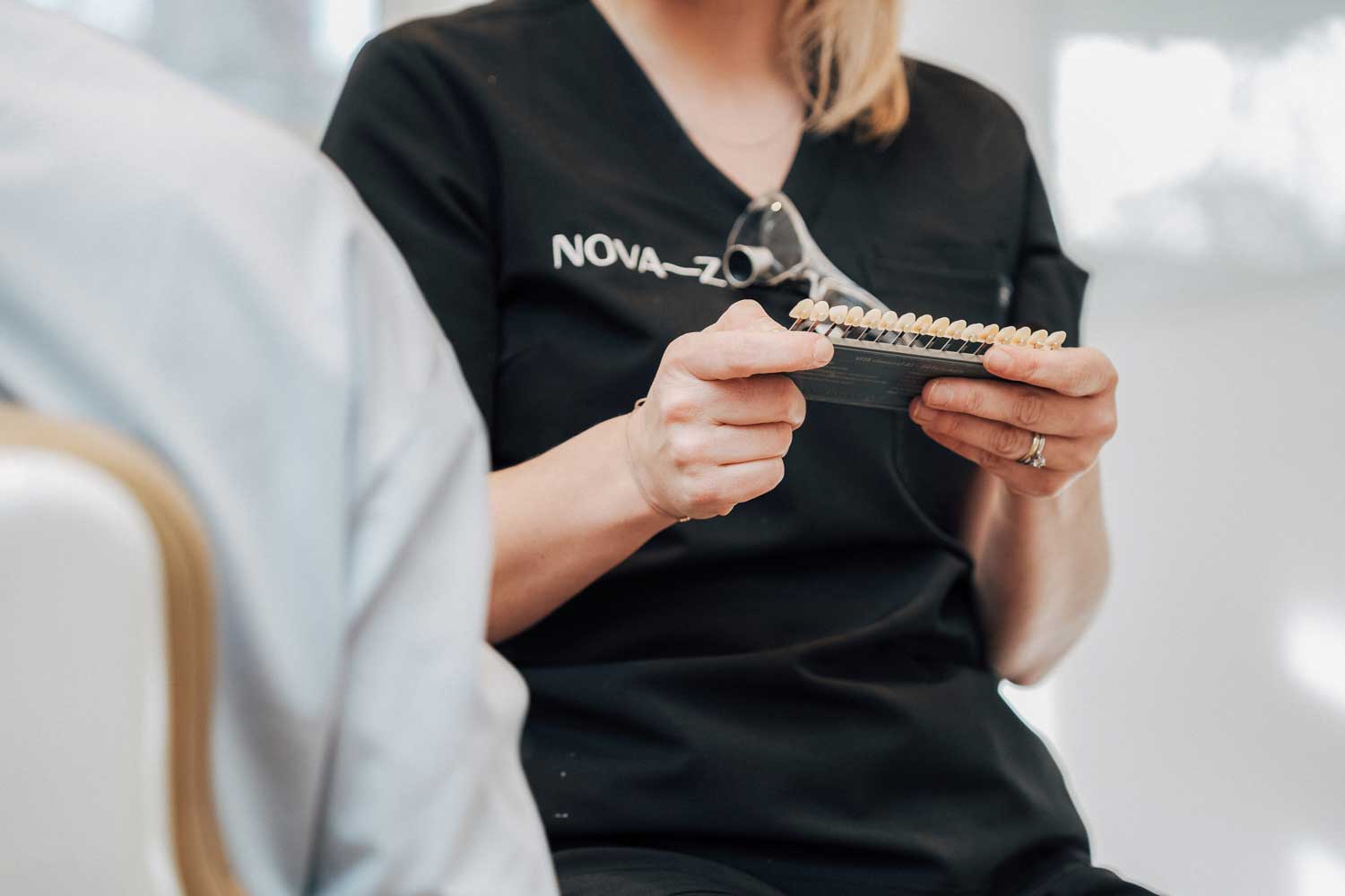 Eine Dentalhygienikerin von NOVA-Z hält eine Zahnpalette in den Händen, anhand derer die Zahnfarbe bei einem Bleaching ausgewählt wird