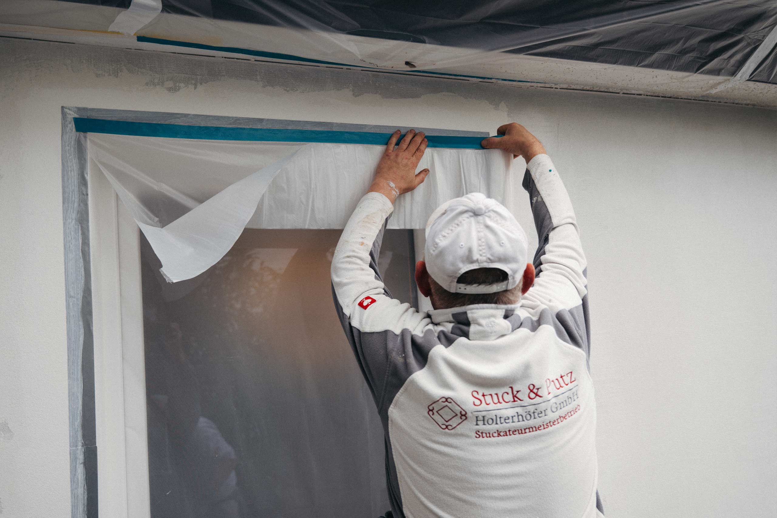 Ein Mitarbeiter von Stuck & Putz klebt eine Tür ab für Malerarbeiten
