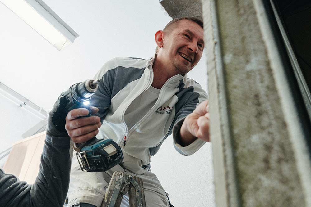 Ein Mitarbeiter von Stuck & Putz bei der Arbeit an einer Außenfassade